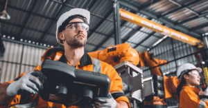 Operator in safety gear using a tablet to monitor tonnage data from a punch press in real-time.