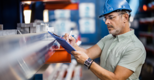 Technician in safety gear inspecting operational metrics on a tablet to ensure press safety and efficiency.