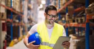 Worker in safety gear analyzing tonnage monitoring data on a tablet to maintain consistent press performance.